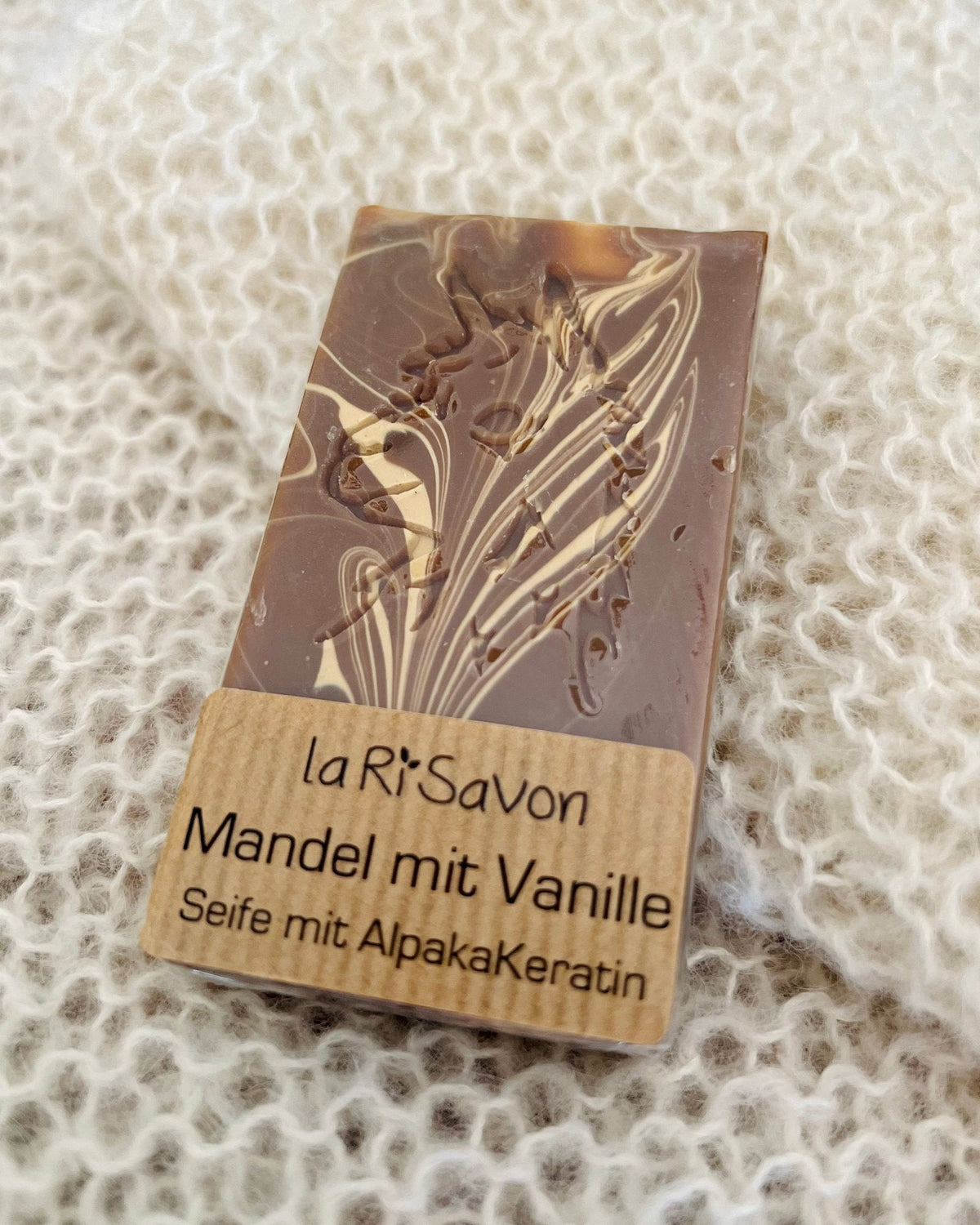 Alpakaseife laRiSavon „Mandel mit Vanille“ – Naturseife mit Alpaka-Keratin auf weißer Strickdecke